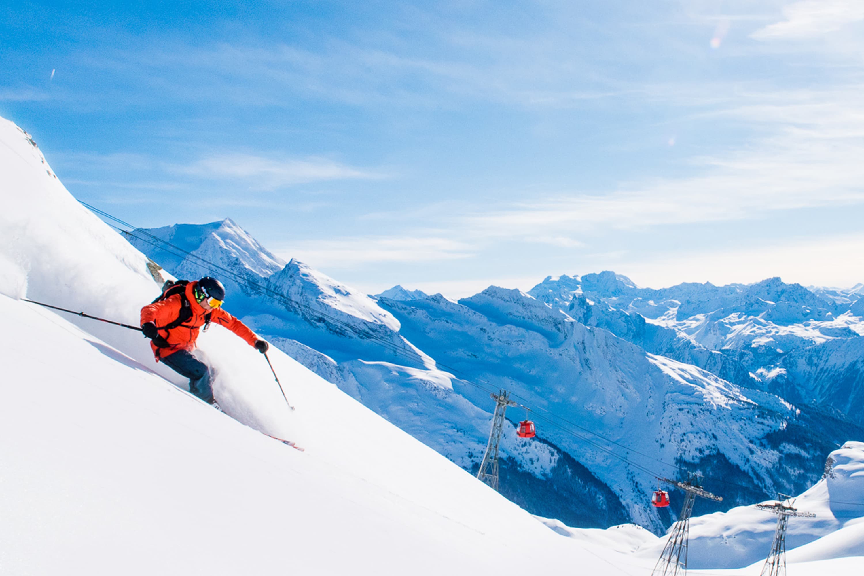 Skiier skiing down off-piste slope on sunny day